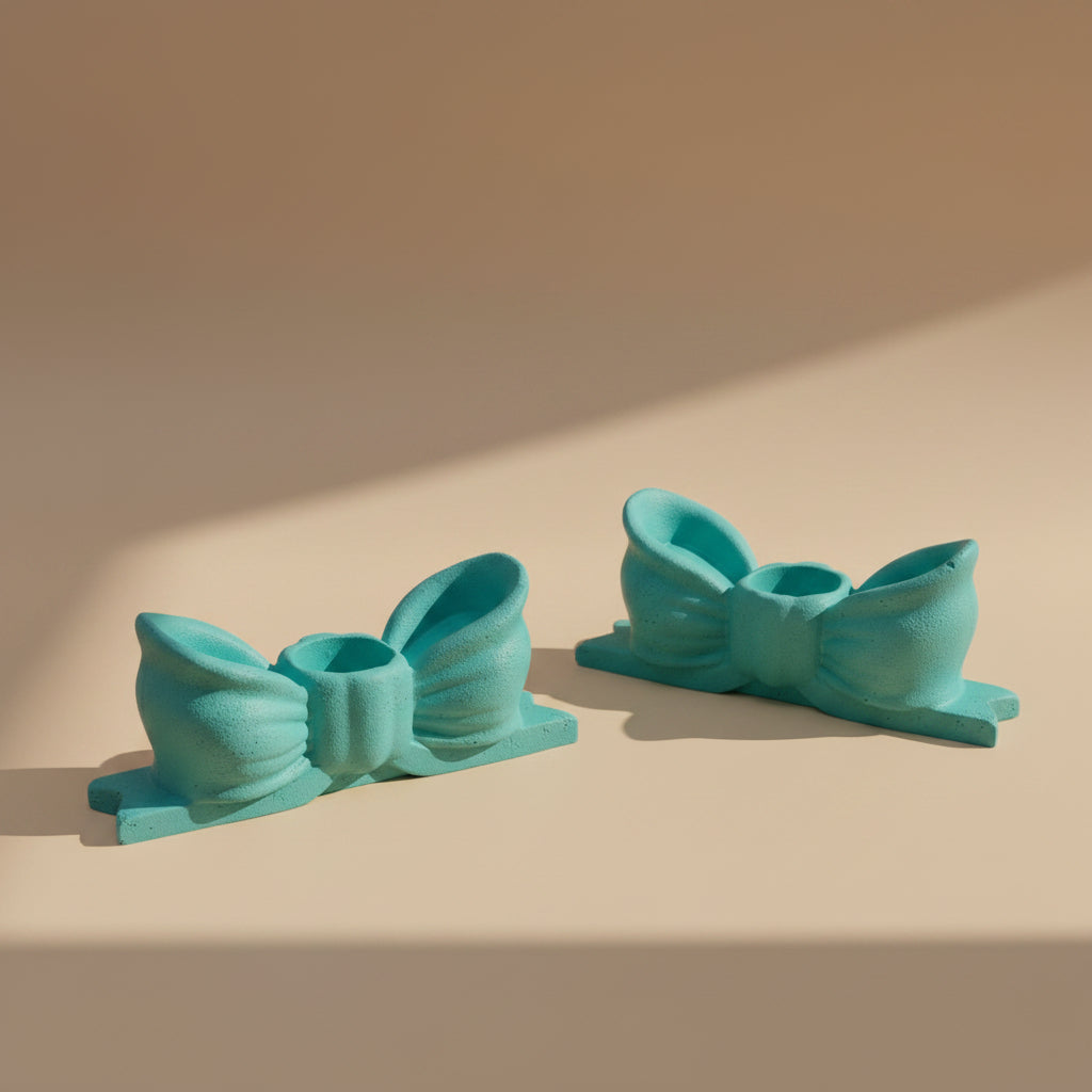 Two turquoise bow-shaped candlestick holders on a beige background