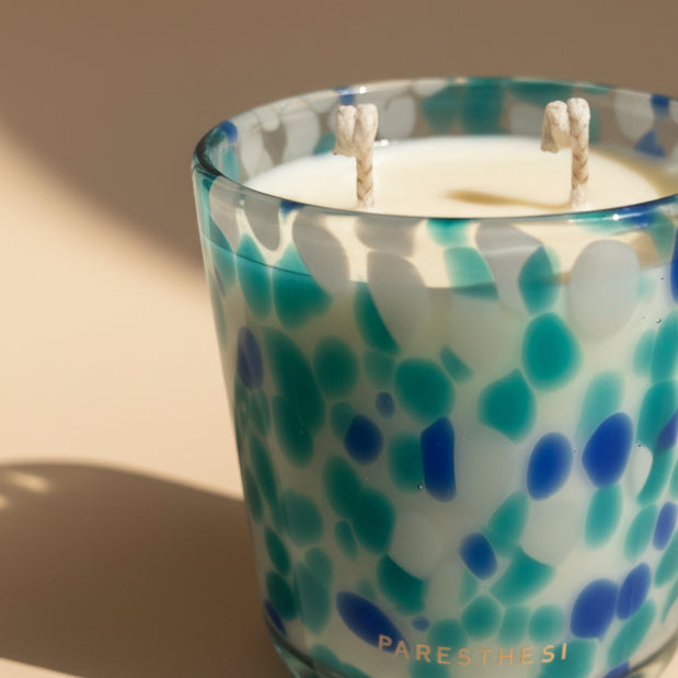 Candle in a glass container with blue and green pattern, featuring the brand 'PARESTHESI'.