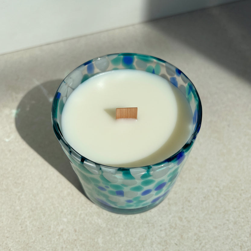 Candle in a glass container with a decorative pattern on a light surface