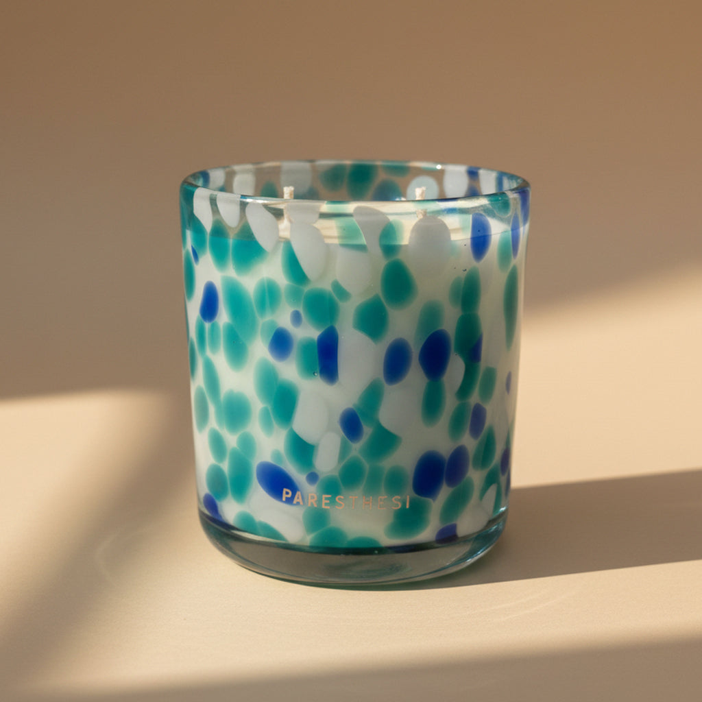 Candle in a glass container with blue and green pattern, featuring the brand 'PARESTHESI'.