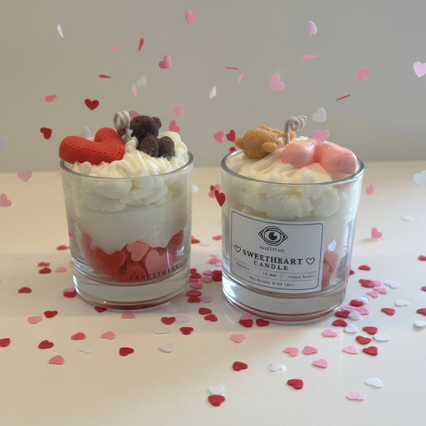 Two decorative candles with teddy bears and heart shapes on a surface with heart confetti.