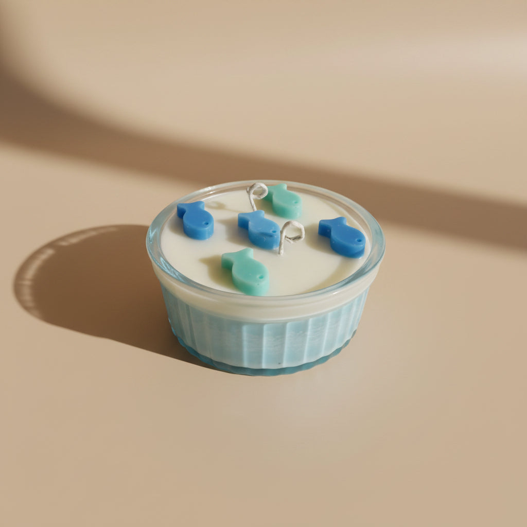 Candle with blue and green decorative fish on a beige background