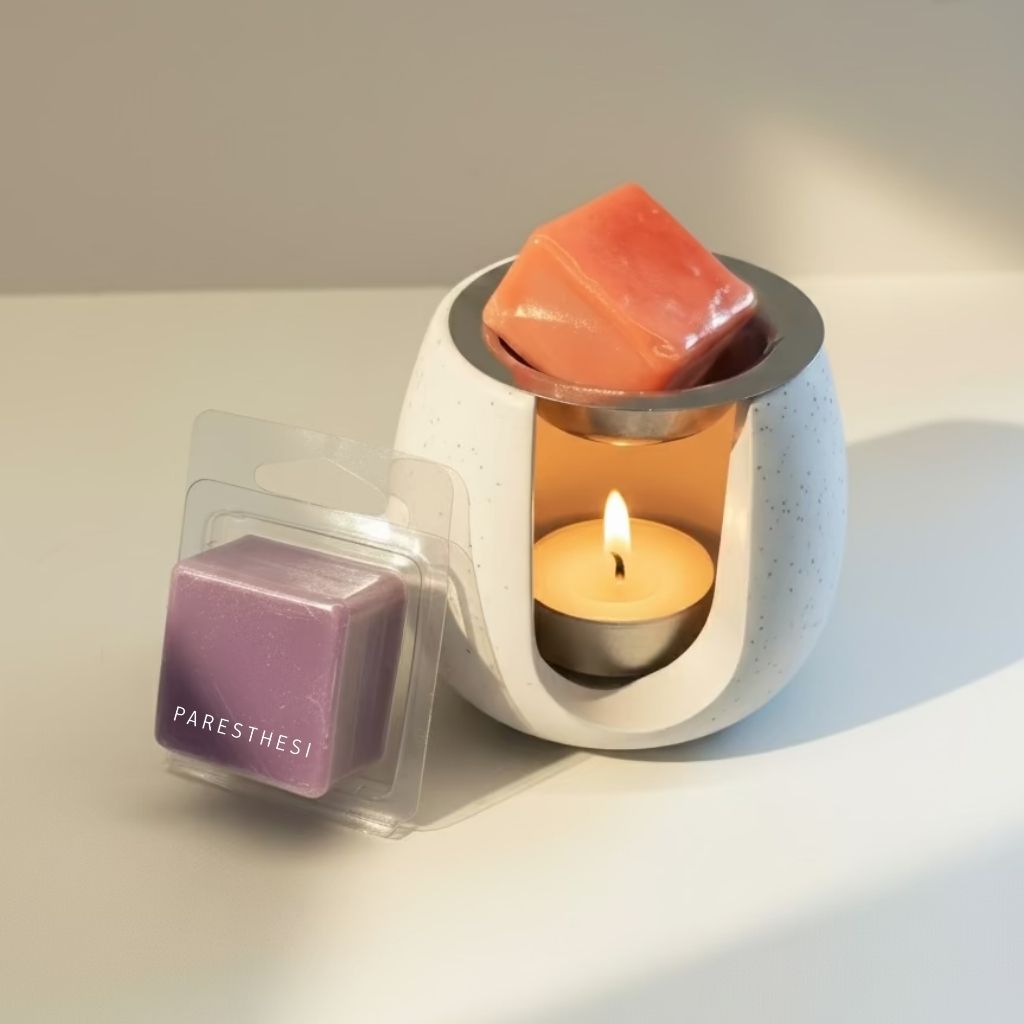 Candle warmer with two wax cubes and a lit candle on a neutral background