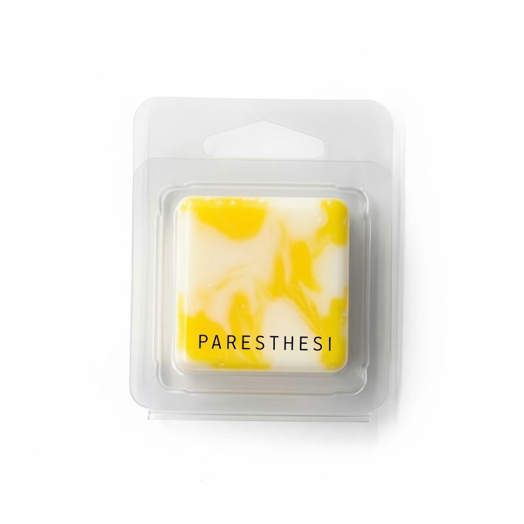 Yellow and white marbled wax melt in clear packaging on a gray background
