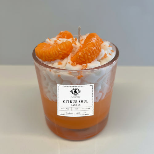 Candle with orange slices in a glass jar on a white surface