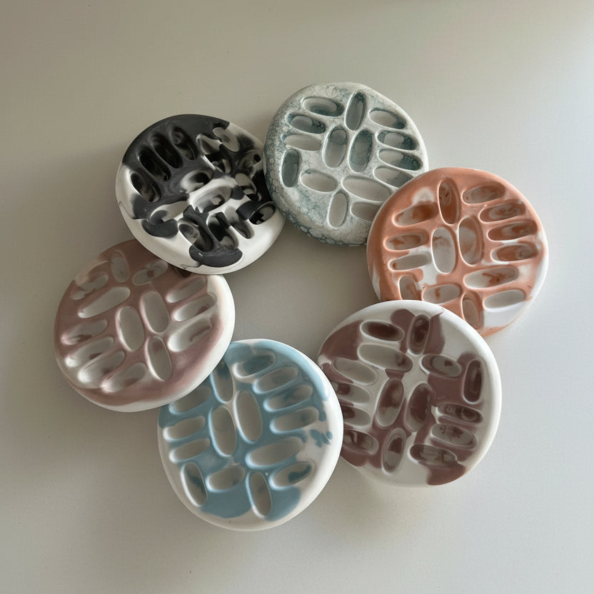 Set of six porcelain jewelry trays in various colors on a light background